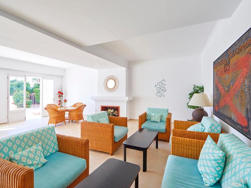 Bright, modern hotel lounge with wicker furniture, blue cushions, and large wall art.