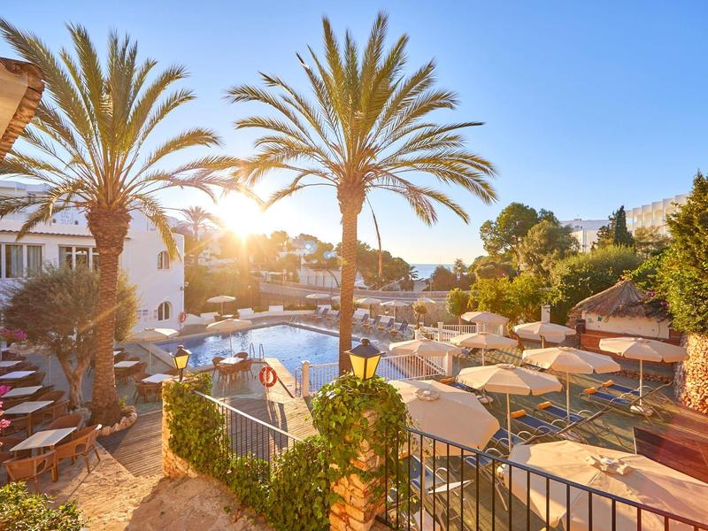 Sunny hotel pool area with palm trees and sun loungers for relaxation.