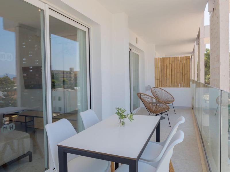 Balcone moderno con tavolo da pranzo e sedie in una camera d'hotel con ringhiera in vetro.