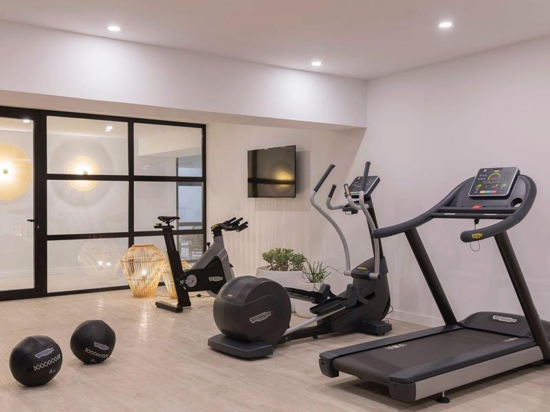 Palestra moderna con tapis roulant, ellittica, manubri e palle mediche.