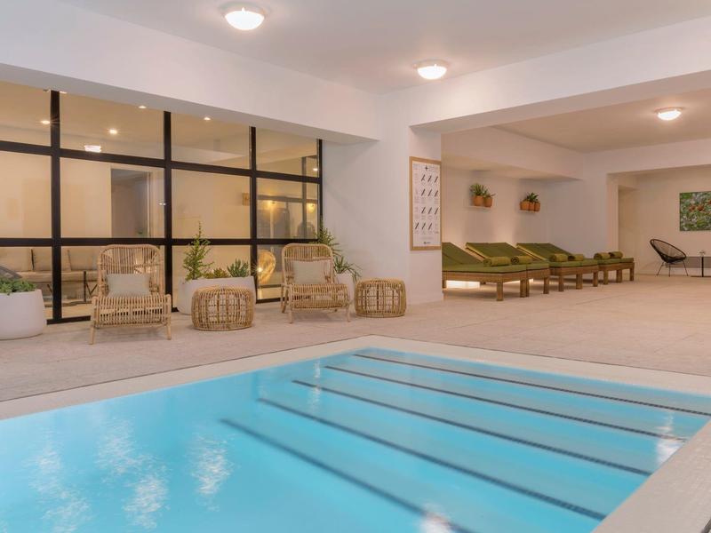 Area interna con piscina illuminata, poltrone e lettini in un hotel