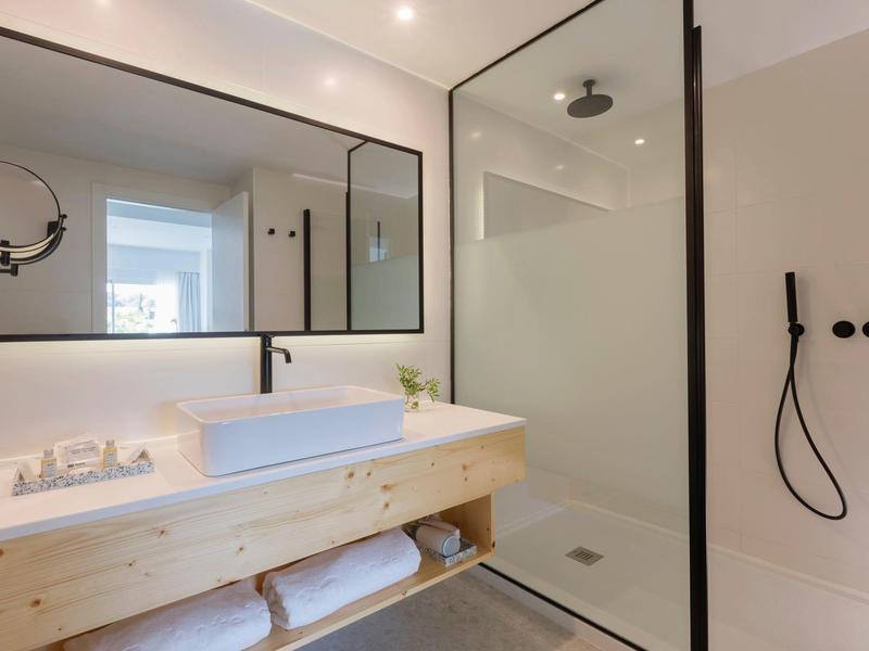 Bagno moderno con mobile in legno, grande specchio e doccia in vetro.