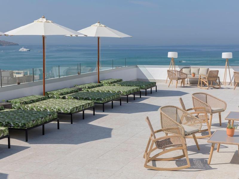 Terrazza sul tetto moderna con lettini e ombrelloni con vista sul mare.