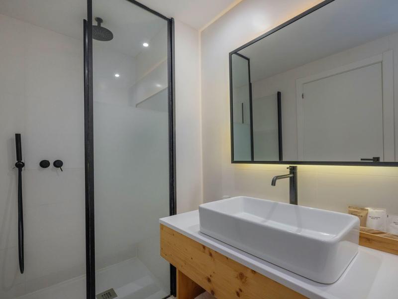 Bagno moderno con ampia doccia in vetro e lavabo rettangolare su mobile in legno.