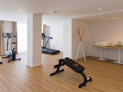 Sala fitness moderna con attrezzature e pavimento in legno chiaro in un hotel.