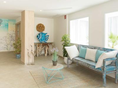 Sala luminosa con sofá azul, mesa de centro de vidrio y plantas junto a la ventana.