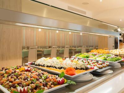 Línea de buffet con varias ensaladas y platos en un restaurante de hotel moderno.