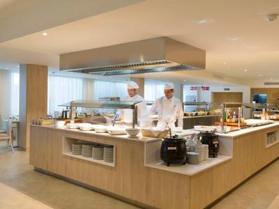 Cocina moderna de hotel con estación de cocina, dos chefs y interior luminoso.