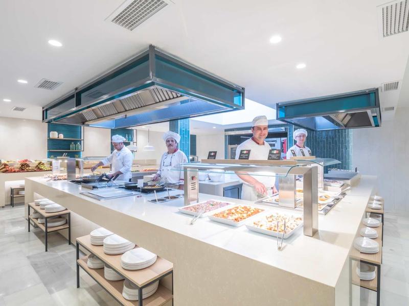 Moderne, helle Cafeteria mit Bedienungstheke, Köchen und gedeckten Tischen in minimalistischem Design.