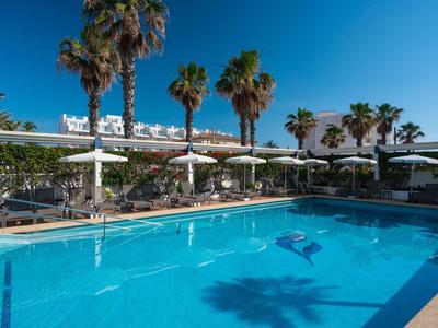 Swimmingpool mit Palmen, Sonnenschirmen und Sitzbereichen bei klarem Himmel