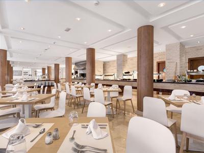 Helles Restaurant mit Holzböden, weißen Stühlen und aufwendig gedeckten Tischen.