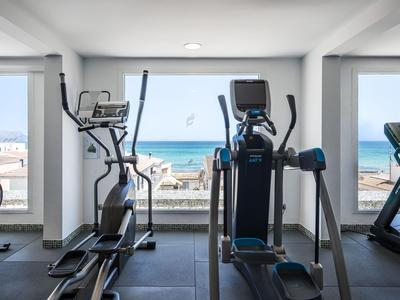 Moderner Fitnessraum mit Cardiogeräten und Meerblick durch große Fenster.