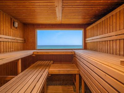 Holzsauna mit Bankreihen und Fenster mit Blick auf den blauen Himmel.