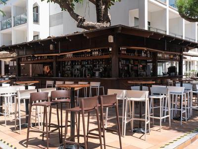 Moderner Außenbereich einer Bar mit hohen Tischen und Stühlen in einem Hotel.