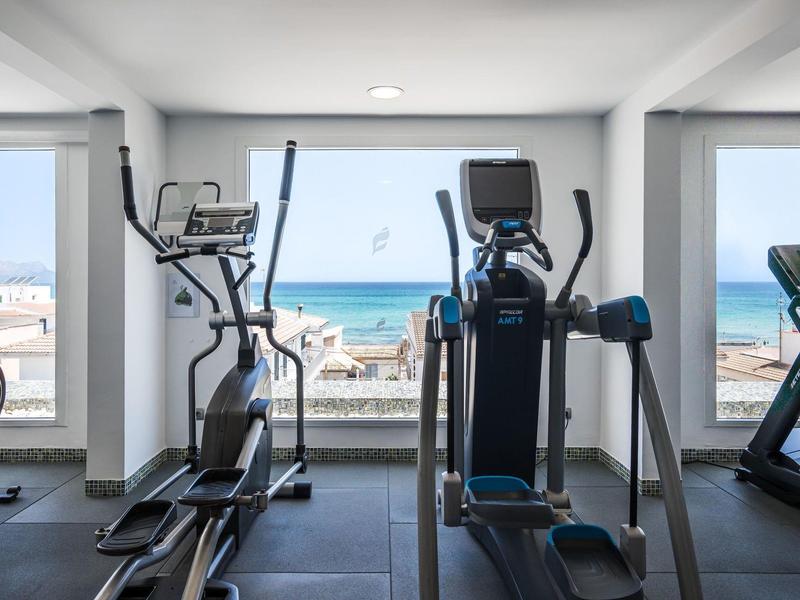 Moderner Fitnessraum mit Blick auf das Meer durch große Fenster.