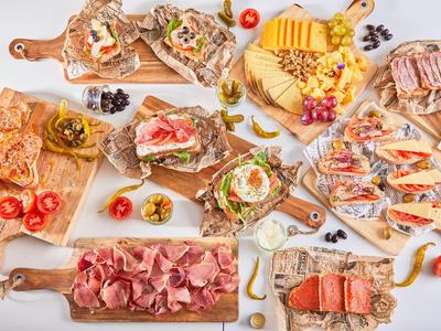 Variedad de bocadillos abiertos y embutidos dispuestos en tablas de madera.