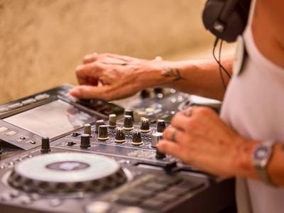 Manos en una consola de DJ con auriculares en un ambiente relajado.