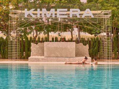 Una piscina moderna con un letrero blanco de Kimera y dos personas en el agua.