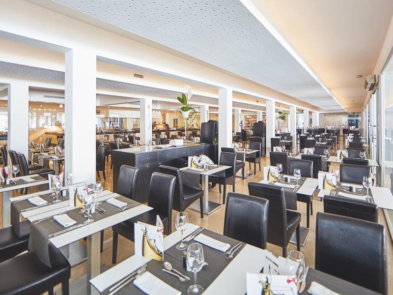 Restaurante moderno y luminoso con asientos negros y grandes ventanales para mucha luz natural.