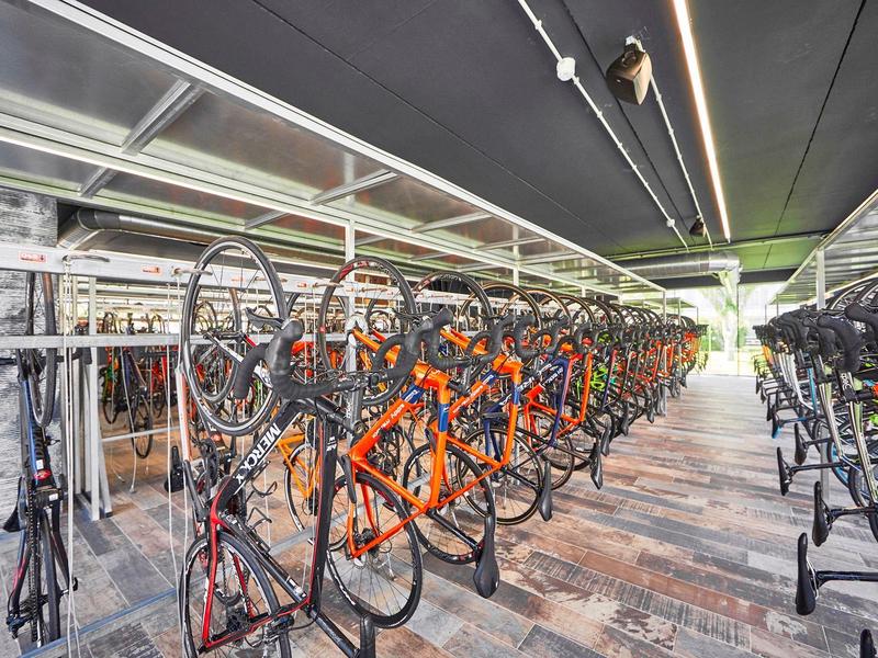 Estacionamiento de bicicletas con varias bicicletas estacionadas junto a un edificio moderno.