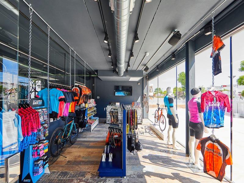 Tienda luminosa de bicicletas y ropa deportiva con grandes ventanas y diseño moderno.