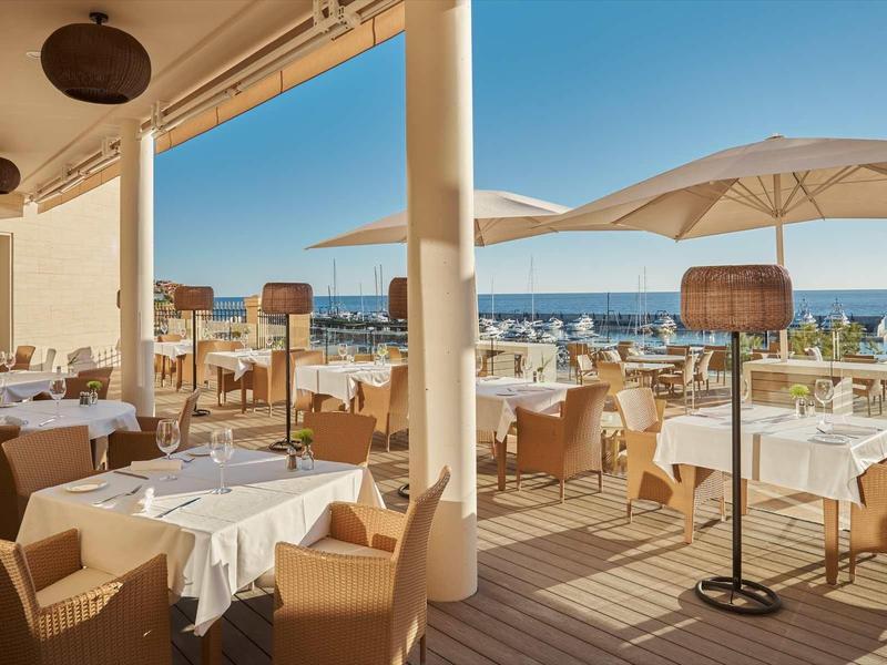 Terrace with set tables and sea view under clear sky.