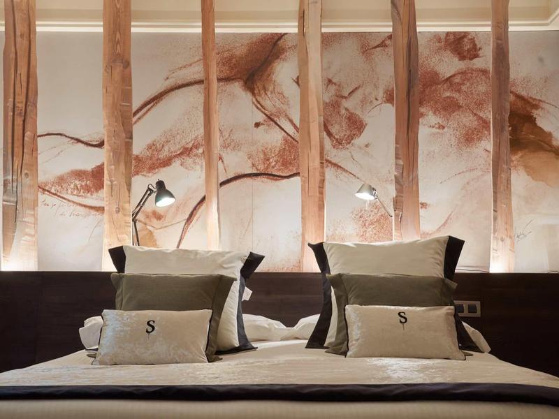 Modern double bed with comfortable pillows and natural wood divider in hotel room.