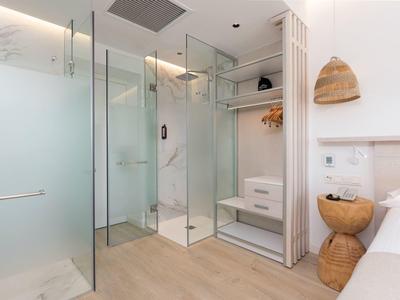 Modern bathroom with glass shower, wooden shelf, and bright interior in hotel room.