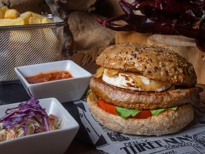 Burger with sesame bun, lettuce, tomato, egg, and fries served with two dips.