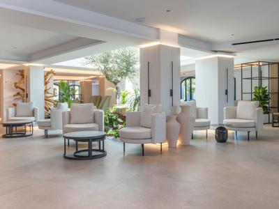 Hall d'hotel moderno con poltrone comode, tavoli e piante.