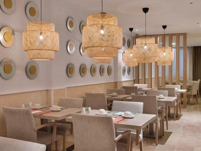 Modern restaurant with wooden tables, upholstered chairs, and decorative wall lights.