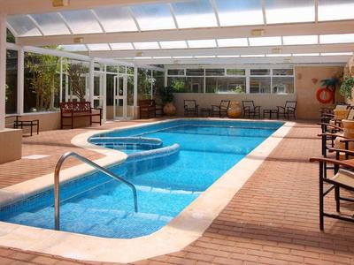 Indoor pool with blue tiles, surrounded by wooden flooring and seating