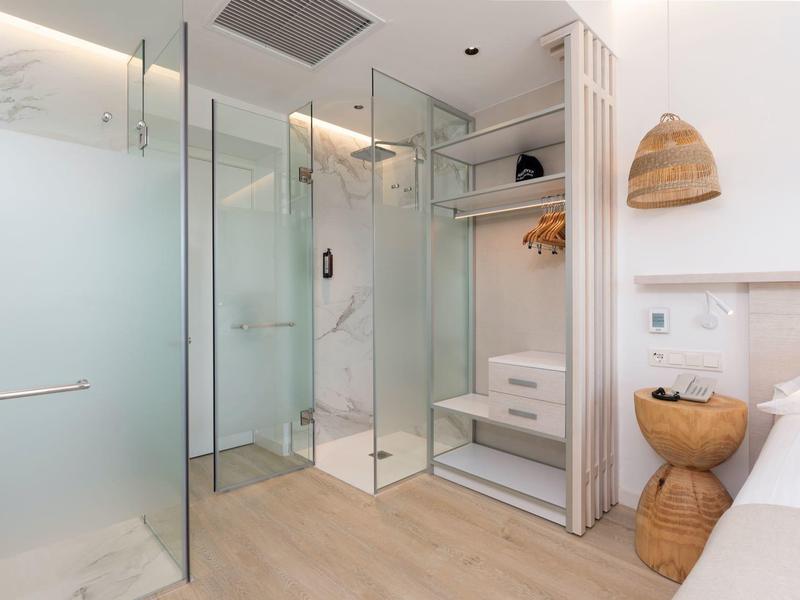 Modern bathroom with glass shower, wooden shelf, and bright interior in hotel room.