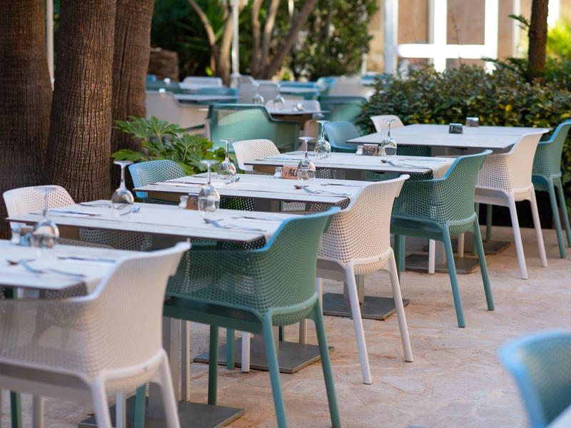 Outdoor restaurant area with neatly set tables and various chairs.