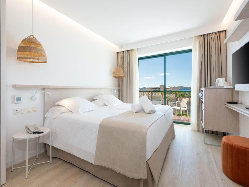 Bright double room with large bed, modern furniture, and balcony with a view.