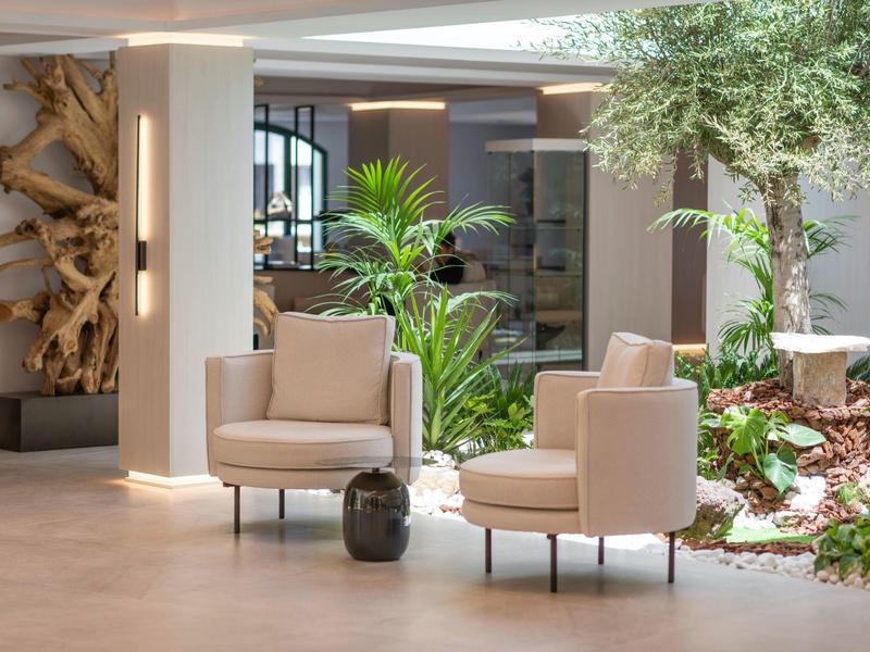 Modern hotel area with comfortable chairs and green plants.