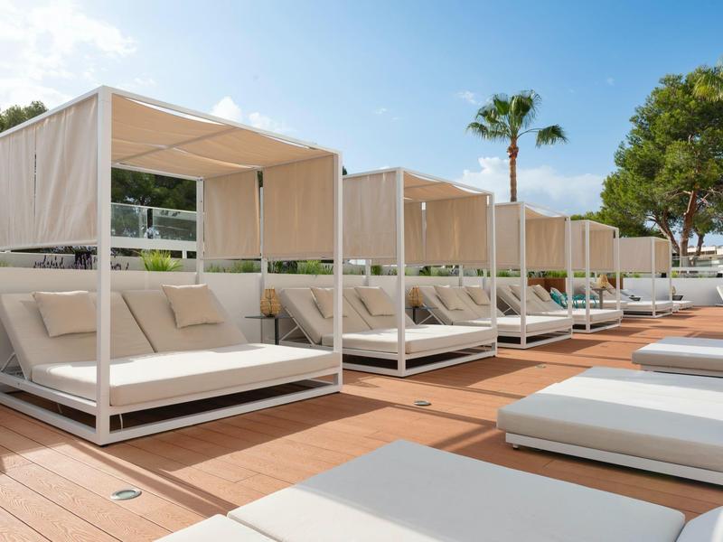 Modern white lounge beds with canopies by the pool in sunny weather