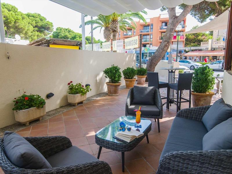 Przytulny taras z meblami z rattanu, stolik z napojami i widokiem na ulicę.