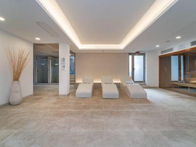 Moderner Wellnessraum mit Liegen, großen Fenstern und gedämpfter Beleuchtung.