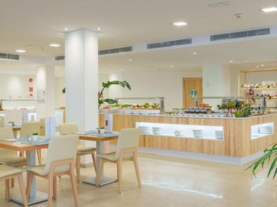 Lichte hotellobby met wit en houtkleurig meubilair en buffetgedeelte.