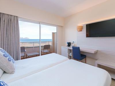 Modernes Hotelzimmer mit zwei Einzelbetten, Schreibtisch und Meerblick vom Balkon.