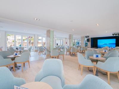 Modern eingerichteter, heller Hotel-Loungebereich mit blauen Sesseln und großen Fenstern.