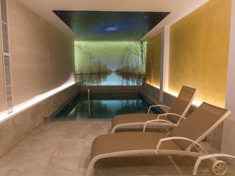 Entspannungsbereich mit Liegestühlen und beleuchtetem Schwimmbecken in modernem Raum