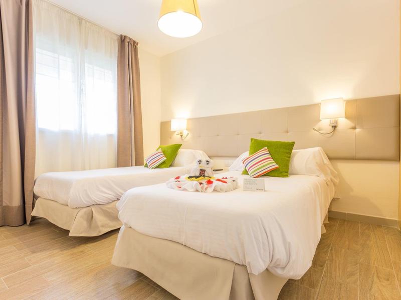 Hotelzimmer mit zwei Einzelbetten, weißen Bettwäsche und einer Blume auf dem Bett