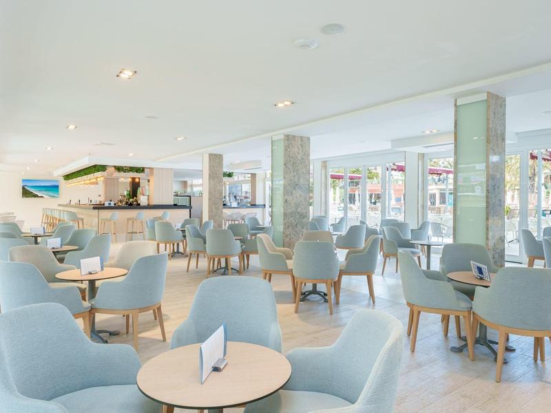 Modern eingerichteter heller Hotel- oder Cafébereich mit blauen Sesseln und kleinen Tischen.