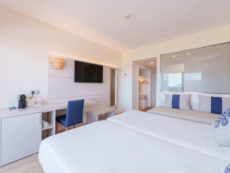 Modernes Hotelzimmer mit Doppelbett, Schreibtisch, Fernseher und Badezimmer im Hintergrund.