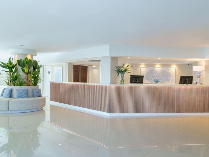 Helle Hotel-Lobby mit modernem Empfangstresen und einem runden Blumenarrangement.