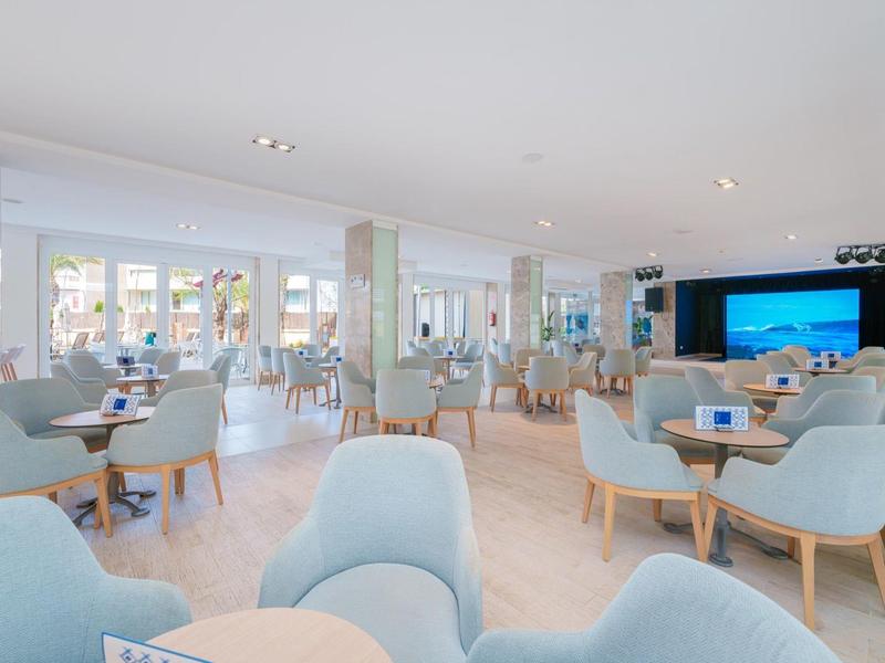 Modern eingerichteter, heller Hotel-Loungebereich mit blauen Sesseln und großen Fenstern.