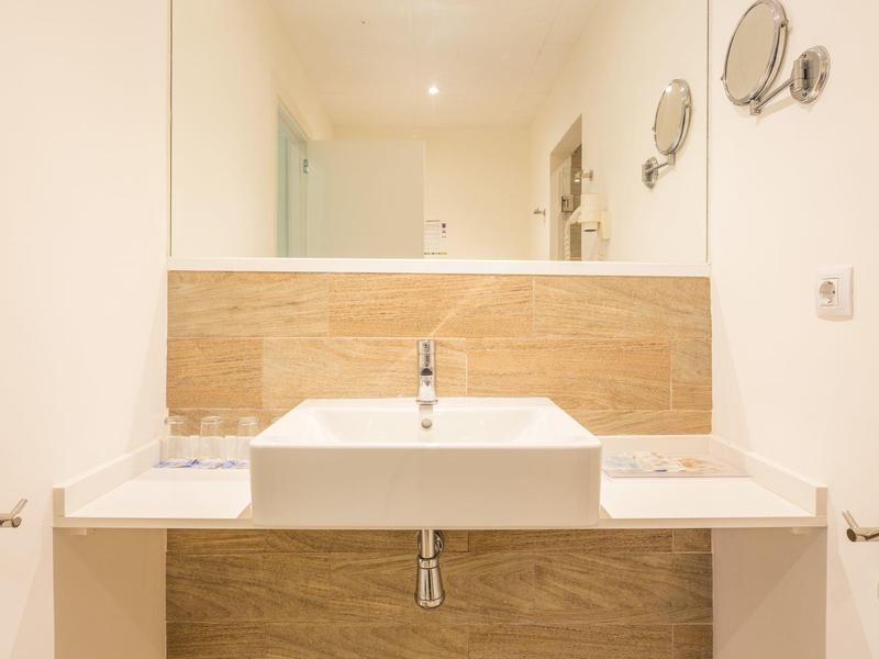 Modernes Badezimmer mit weißem Waschbecken und beige gefliester Wand