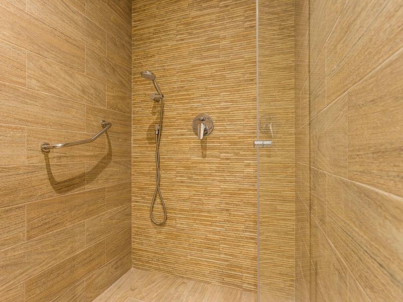 Moderne Dusche mit braunen Fliesen und Handbrause in einem Hotelzimmer